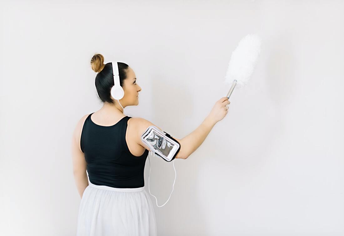 A woman dusting and listening to music
