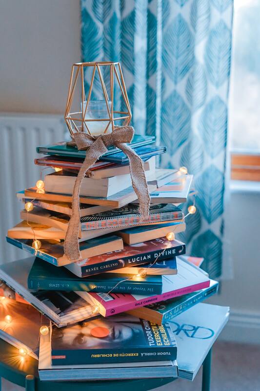 A stack of books with lights and a candle on top
