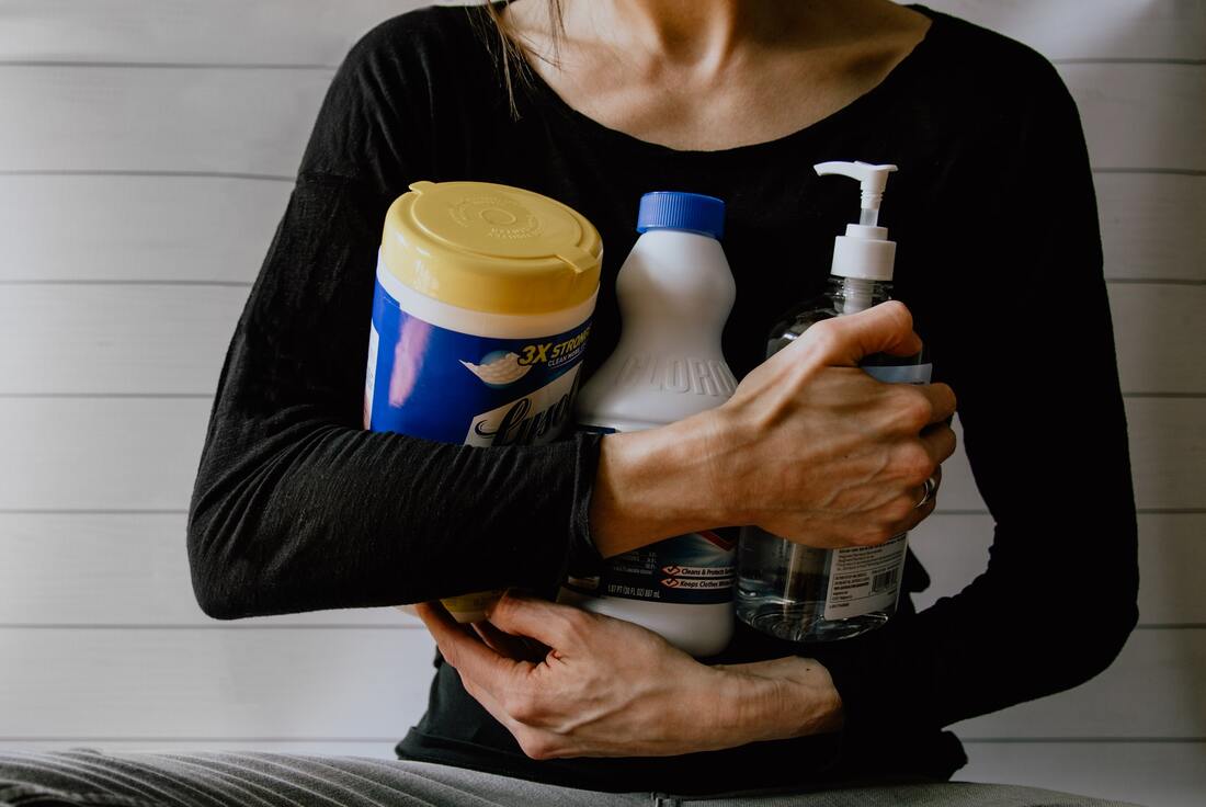 A woman holding cleaning supplies as a way to prepare for spring cleaning